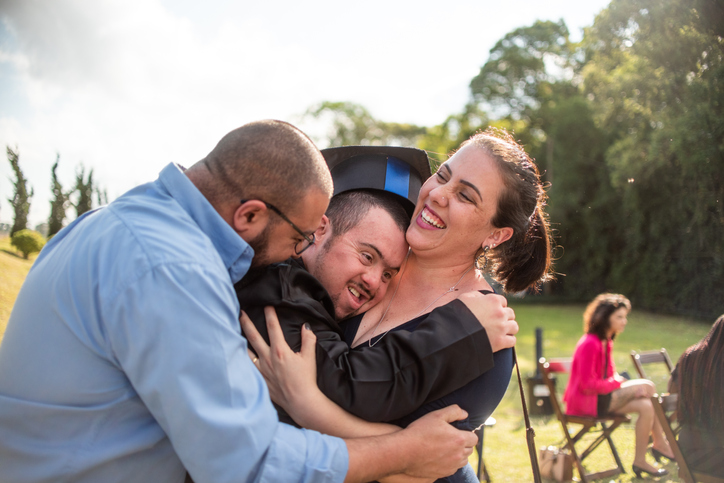 Family members hugging the graduate with down syndrome