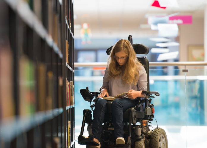 Handicapped Girl with motorized wheelchair In Library